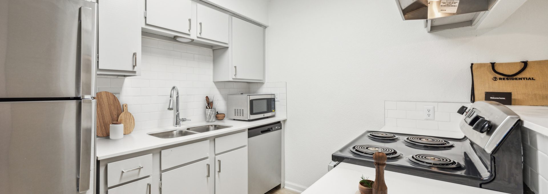 a kitchen with stainless steel appliances and white cabinets at The Falltree Apartments