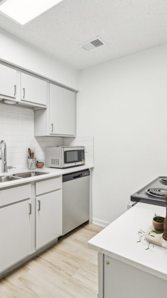 a kitchen with stainless steel appliances and white cabinets at The Falltree Apartments
