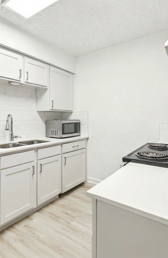 a kitchen with stainless steel appliances and white cabinets at The Falltree Apartments